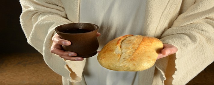 Jesus hands holding bread and wine over dark background